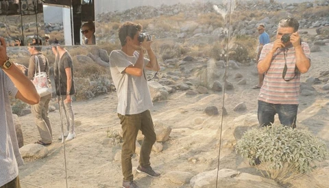 Photographers shooting in a desert landscape with rock formations visible through glass panels.