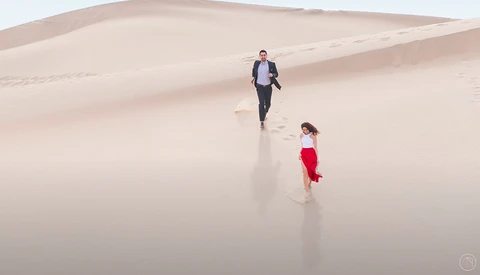 Man and child walking across a vast, wet sand beach with soft, diffused lighting.