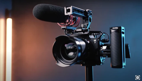 Professional mirrorless camera rig with shotgun microphone, wireless receiver, and follow focus system mounted on tripod.