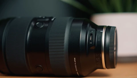 Sigma zoom lens with focusing ring and distance scale markings, positioned horizontally on wooden surface.