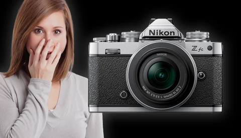 Woman with surprised expression beside a Nikon Z fc mirrorless camera on black background.