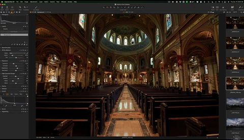 Interior of a grand cathedral with ornate wooden pews lining a central aisle, illuminated by stained glass windows and warm architectural lighting.
