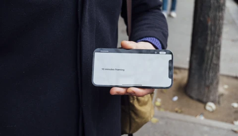 Person in dark clothing holding a smartphone displaying a loading screen with text.