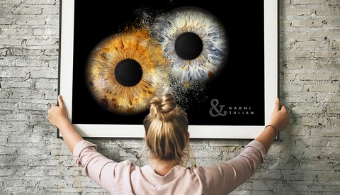 Large framed print displaying two close-up human irises—one golden-brown, one blue-gray—against black background.