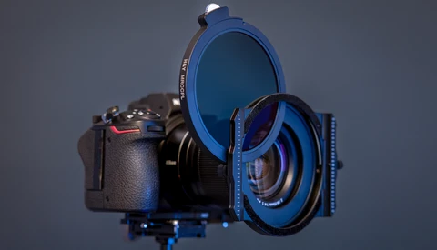 Camera with blue filter system and lens attachments arranged on neutral background.
