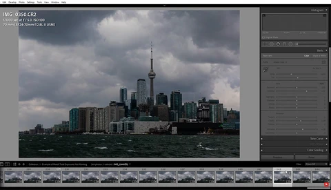 Toronto skyline with CN Tower viewed across Lake Ontario under dramatic cloudy sky.