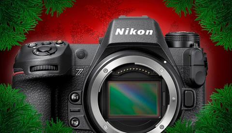 Nikon Z mirrorless camera with body cap removed, displayed against a red background with evergreen garland.