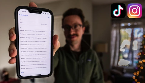 Smartphone displaying a social media feed with multiple posts, held by a person wearing glasses indoors.