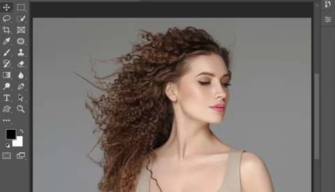 Woman with long, curly brown hair in profile against neutral gray background.