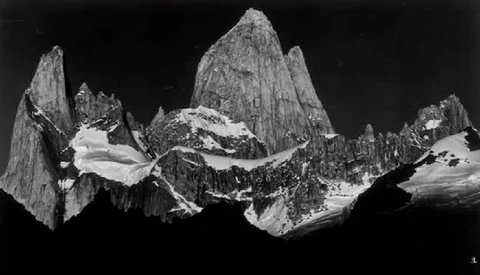 Black and white mountain landscape featuring dramatic granite peaks with glaciers and snow fields against dark sky.