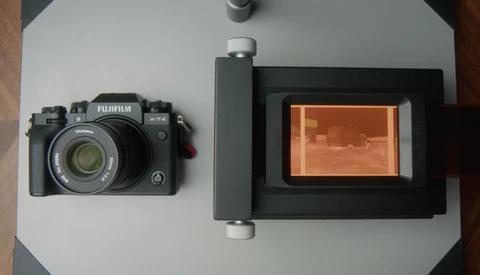 Fujifilm X-T4 camera next to smartphone mount with thermal imaging display on white surface.