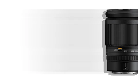 Black telephoto zoom lens with focal length markings visible on the barrel against a light background.