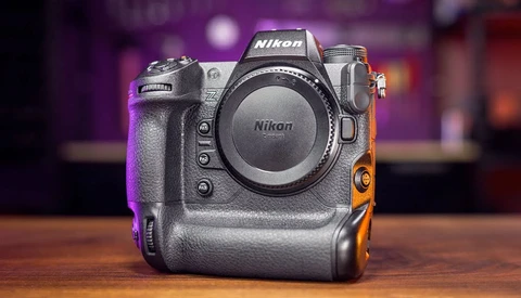 Nikon Z9 mirrorless camera body displayed on wooden surface against blurred colorful background.