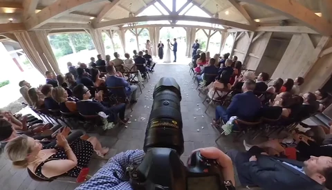 Overhead view of an antique cannon centered in a tent filled with seated spectators on both sides.