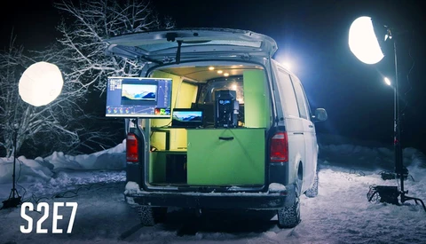 Mobile production van with green interior illuminated at night, surrounded by large LED lighting rigs on stands.