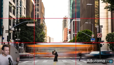 Urban street scene with motion-blurred bus crossing intersection between tall buildings.