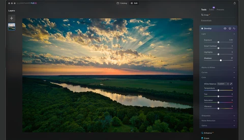 Aerial landscape of a river winding through green fields at golden hour sunset.