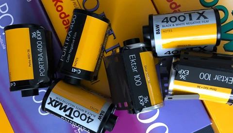 Collection of expired film rolls including Kodak Portra and Ektar stocks arranged on colorful background.