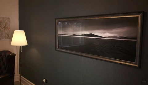 Framed black and white landscape photograph displayed in an interior wall, showing a minimalist composition of water, horizon line, and distant mountains.