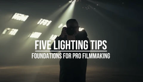 Silhouetted figure backlit by studio lights casting dramatic shadows. Title card reads 'Five Lighting Tips: Foundations for Pro Filmmaking.'