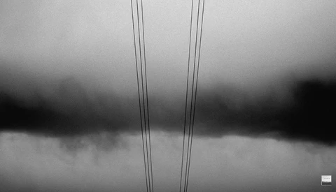 Two parallel power lines against a dramatic cloudy sky in black and white.