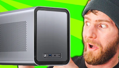 Man with surprised expression next to a compact computer tower against bright green background.