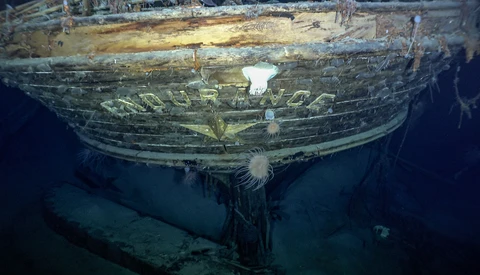 Underwater view of a shipwreck's wooden hull with deteriorated structure and marine growth.