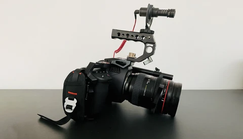 Professional cinema camera with mounted gimbal stabilizer and external microphone on gray surface.