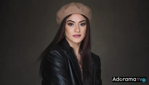 Woman wearing a beige beret and black leather jacket against a dark neutral background.