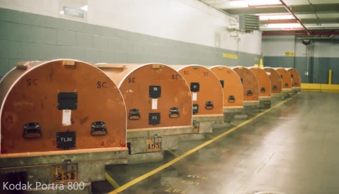 Row of orange metallic pressure vessels or tanks lined up in an industrial facility with green walls.