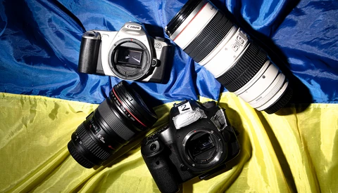 Canon DSLR camera with interchangeable lenses arranged on blue and yellow fabric backdrop.