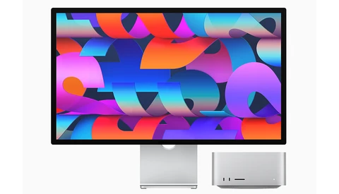Desktop monitor displaying vibrant abstract geometric shapes in magenta, cyan, orange, and blue.
