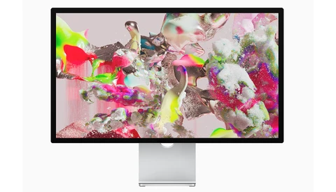 Monitor displaying abstract digital artwork with vibrant magenta, neon yellow, and white particles overlaid on organic forms.