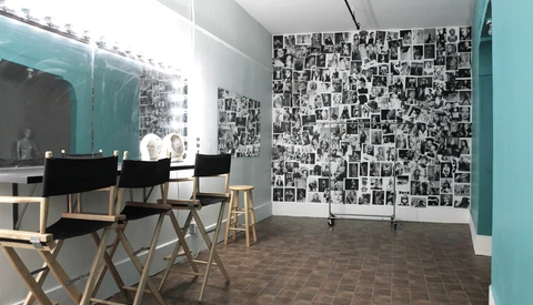 Modern interior space with turquoise accent walls, director's chairs, and gallery wall of black and white photographs.
