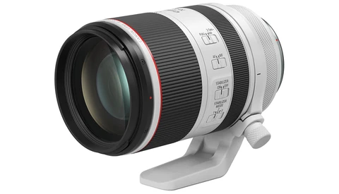 White and black telephoto lens with red accent ring mounted on a white tripod collar.