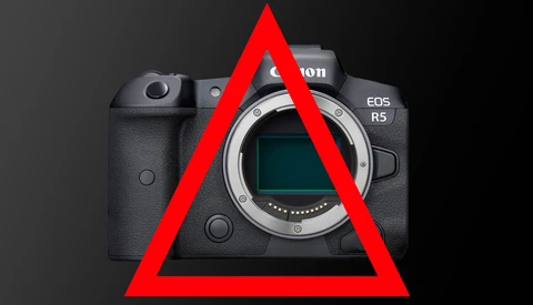 Canon EOS R5 mirrorless camera body with red warning triangle overlaid on front.