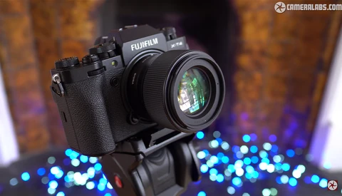 Fujifilm camera mounted on tripod head with bokeh lights in background.
