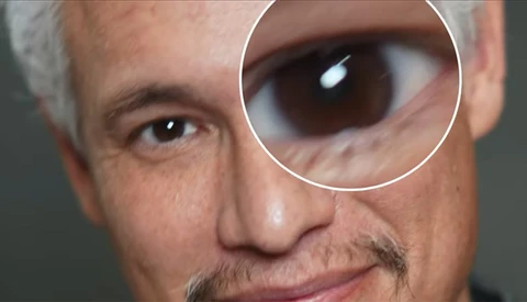 Close-up portrait of a man's face with a magnified circular inset showing extreme detail of his eye.