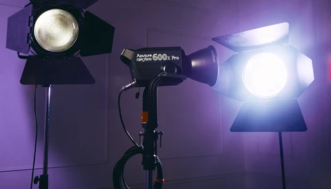 Three professional studio lights with Fresnel lenses positioned in a purple-lit photography setup.
