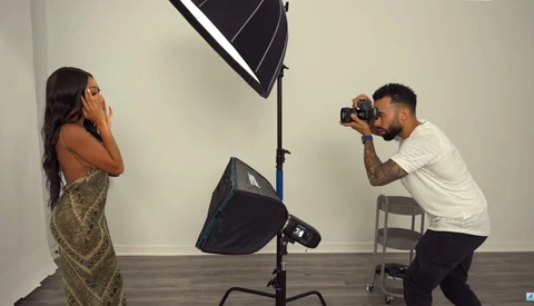 Photographer shooting a portrait subject in a studio with professional lighting setup.