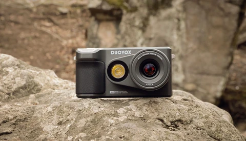 Duoyox instant camera with dual lenses positioned on a textured stone surface.
