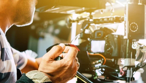 Filmmaker's hands adjusting controls on a cinema camera during production setup.