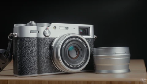 Rangefinder film camera with black leather body and silver metal top plate, displayed with a detached telephoto lens.