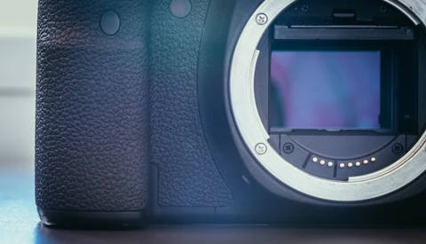 Mirrorless camera body with open sensor mount showing internal mirror and shutter mechanism.