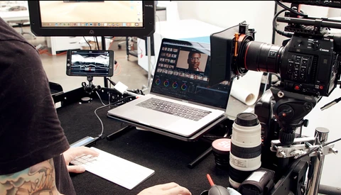 Video production setup with cinema camera, monitors, and editing laptop during a shoot.