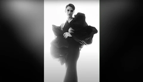 Man in dark suit positioned within an oversized hand against white background.