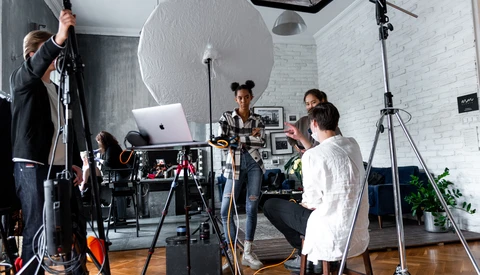 Photography studio setup with crew adjusting lighting equipment and reflectors during a shoot.