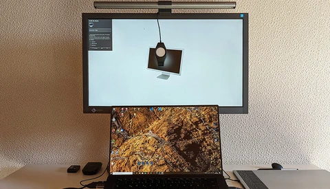 Dual-monitor photography workspace with product visualization software displayed on upper screen and textured landscape image on laptop.