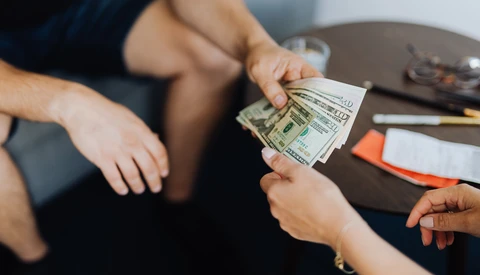 Two people exchanging cash during a financial transaction or payment.