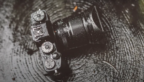 Overhead view of a vintage rangefinder camera with dual exposure dials on a textured dark surface.